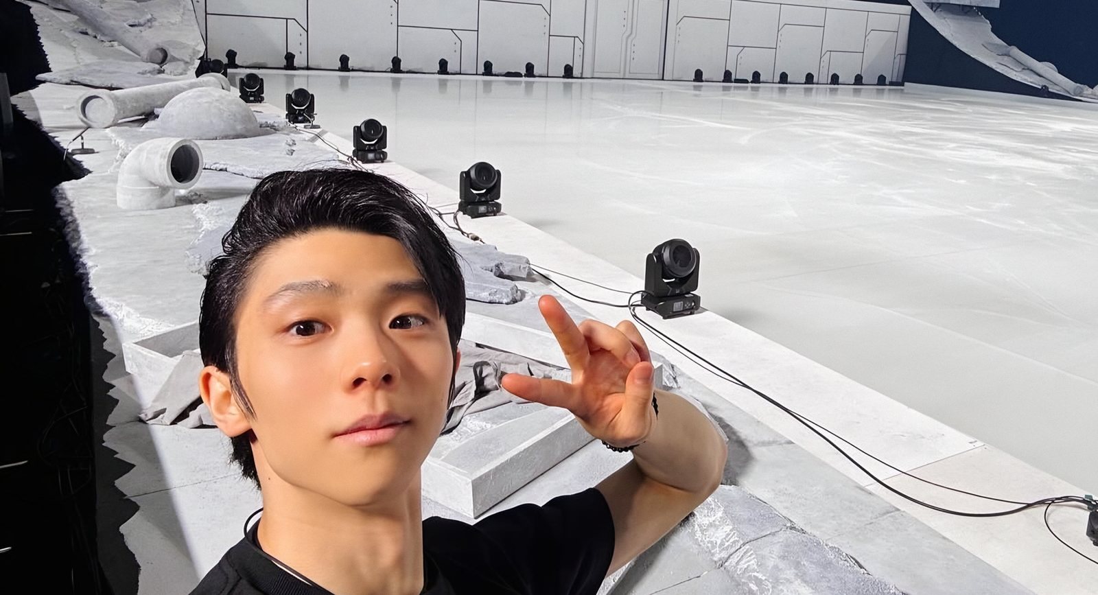 リンクサイドで、照明の並ぶ白い氷を背に笑顔を見せる羽生結弦